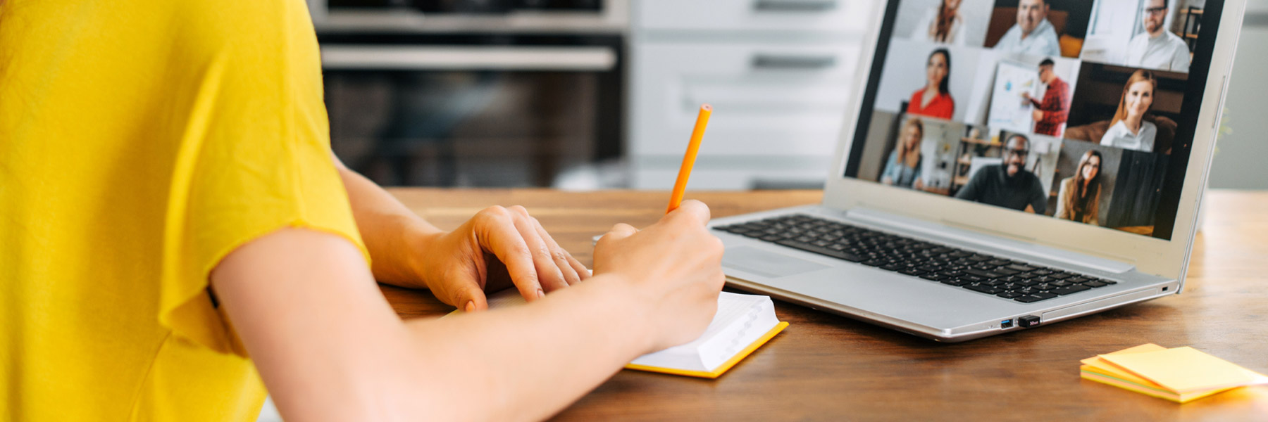 A woman takes notes during a zoom meeting.